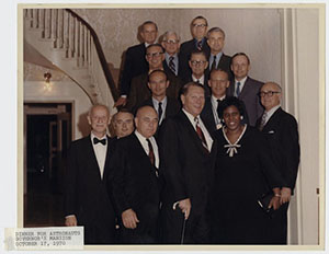 a smiling woman posed next to several smiling men on a long stair-case