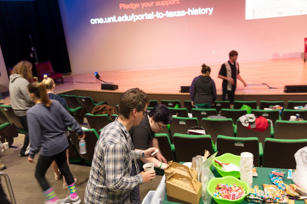 people standing around chairs and a food table