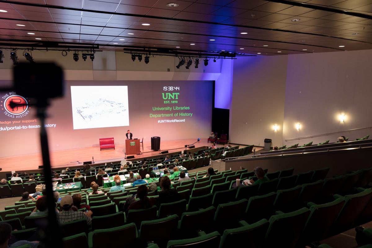 view of a stage and people sitting in chairs