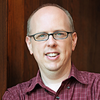 headshot of a smiling man with glasses surrounded by text