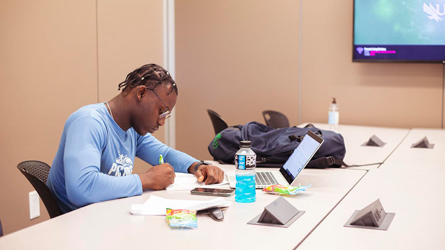 four smiling people sitting at a table with open books