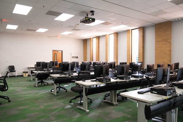computer classroom with computer stations and presentation screen as seen from front-right