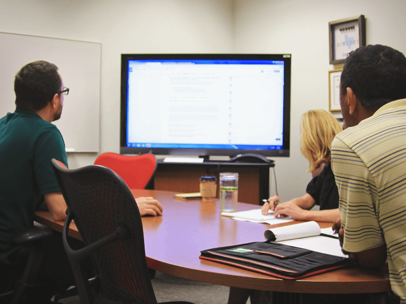 three people looking at a tv screen