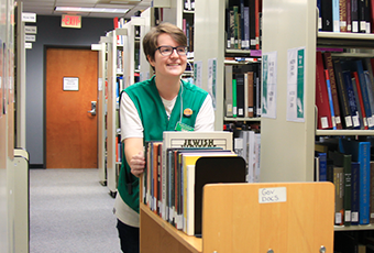 smiling woman pushing book cart