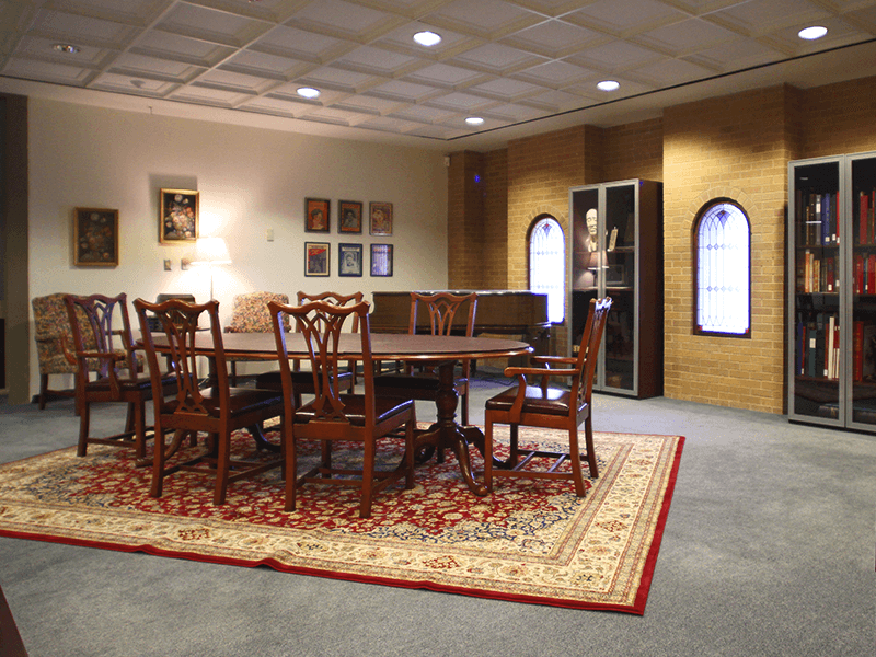 room with tables, chairs, lamp, piano and pictures hung on the wall