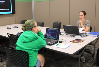 women sitting at a table with laptops